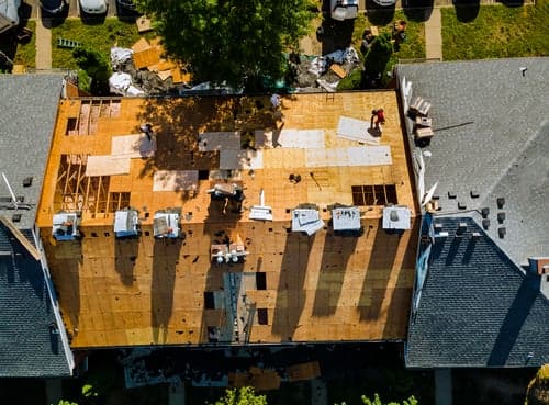 Roofing abc crew mid-replacement on a Miami home, decking exposed and new underlayment going down